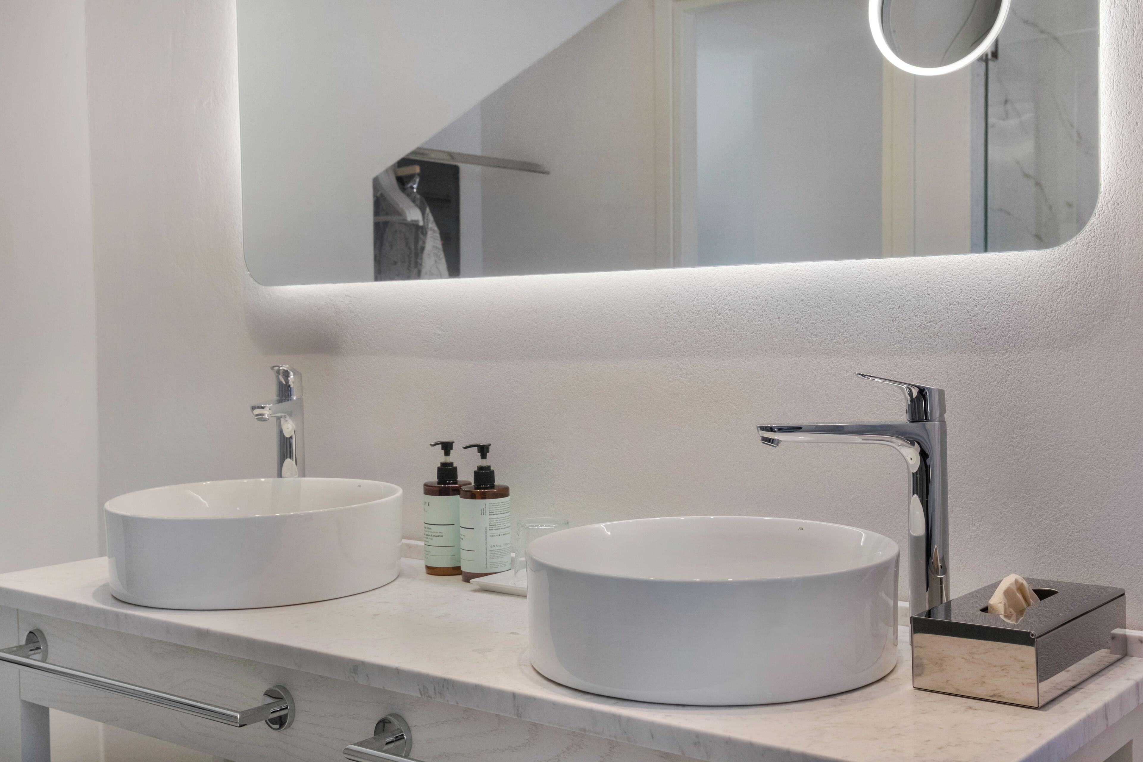 A bathroom with two white sinks, a mirror, and a towel dispenser.