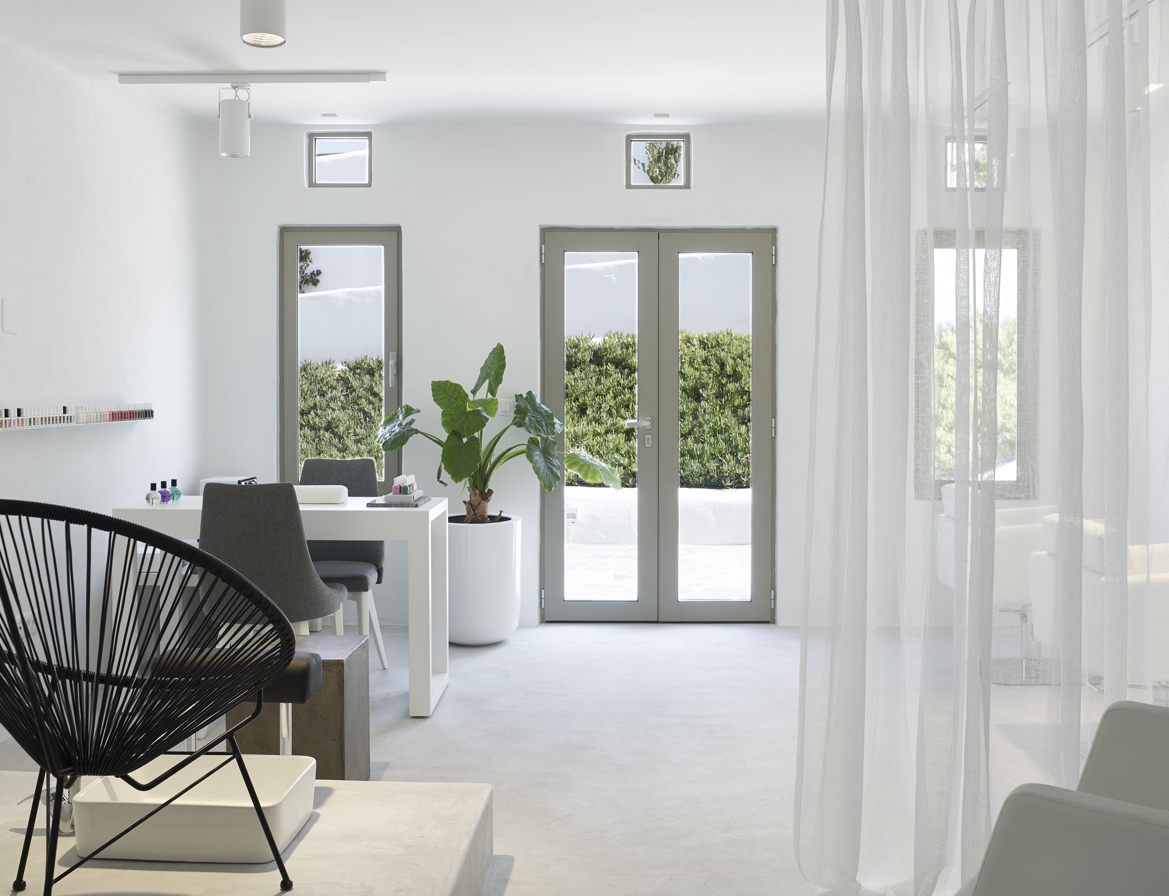 A modern, minimalist room with a desk, chair, and large windows.