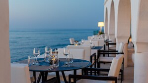 Een restaurant aan zee met gedekte tafels, met uitzicht op de oceaan.