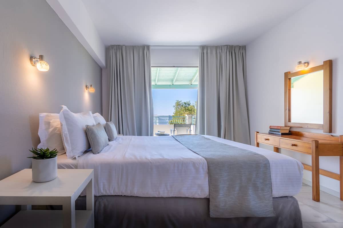 Ein modernes Schlafzimmer mit einem großen Bett, einem Holztisch, einem Spiegel und einer Topfpflanze.