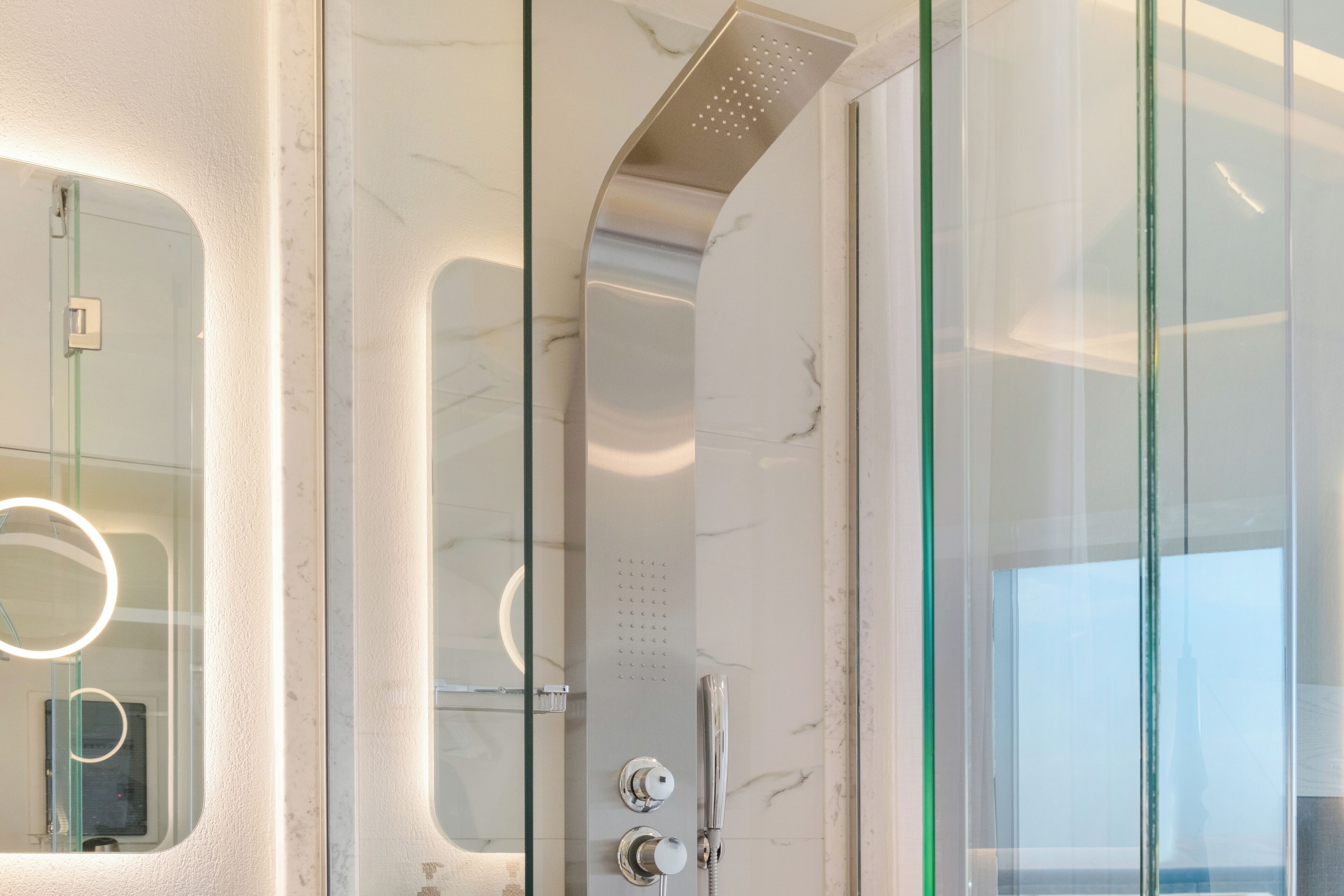 A modern bathroom with a glass shower enclosure, a handheld showerhead, and a handheld faucet.