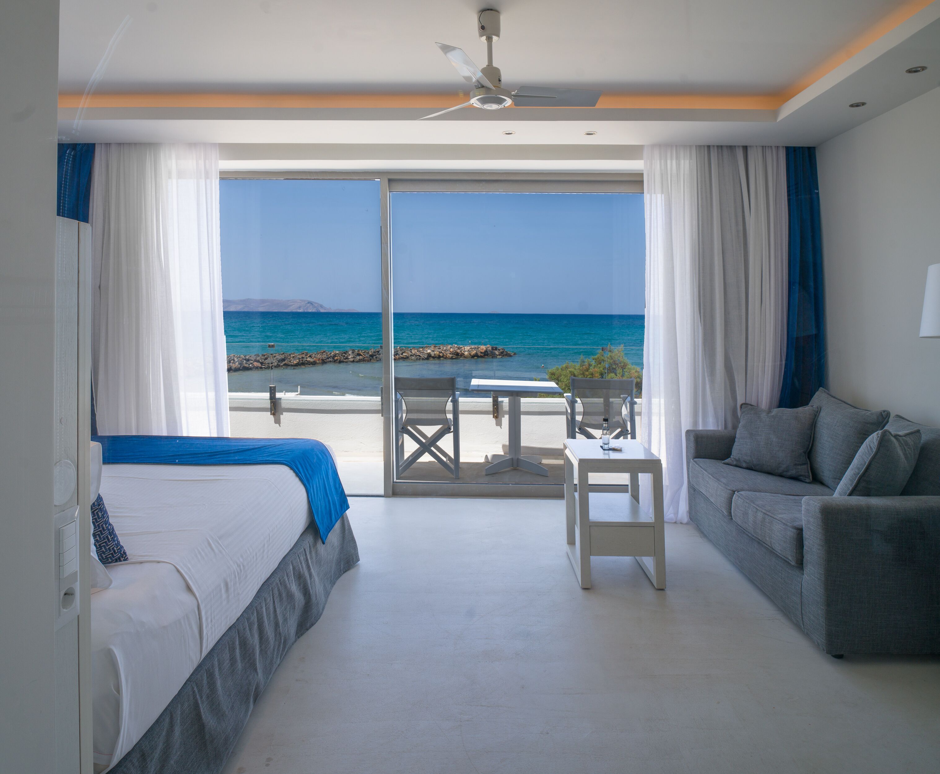 Une chambre d’hôtel avec un lit, un canapé, une table et une vue sur la mer.