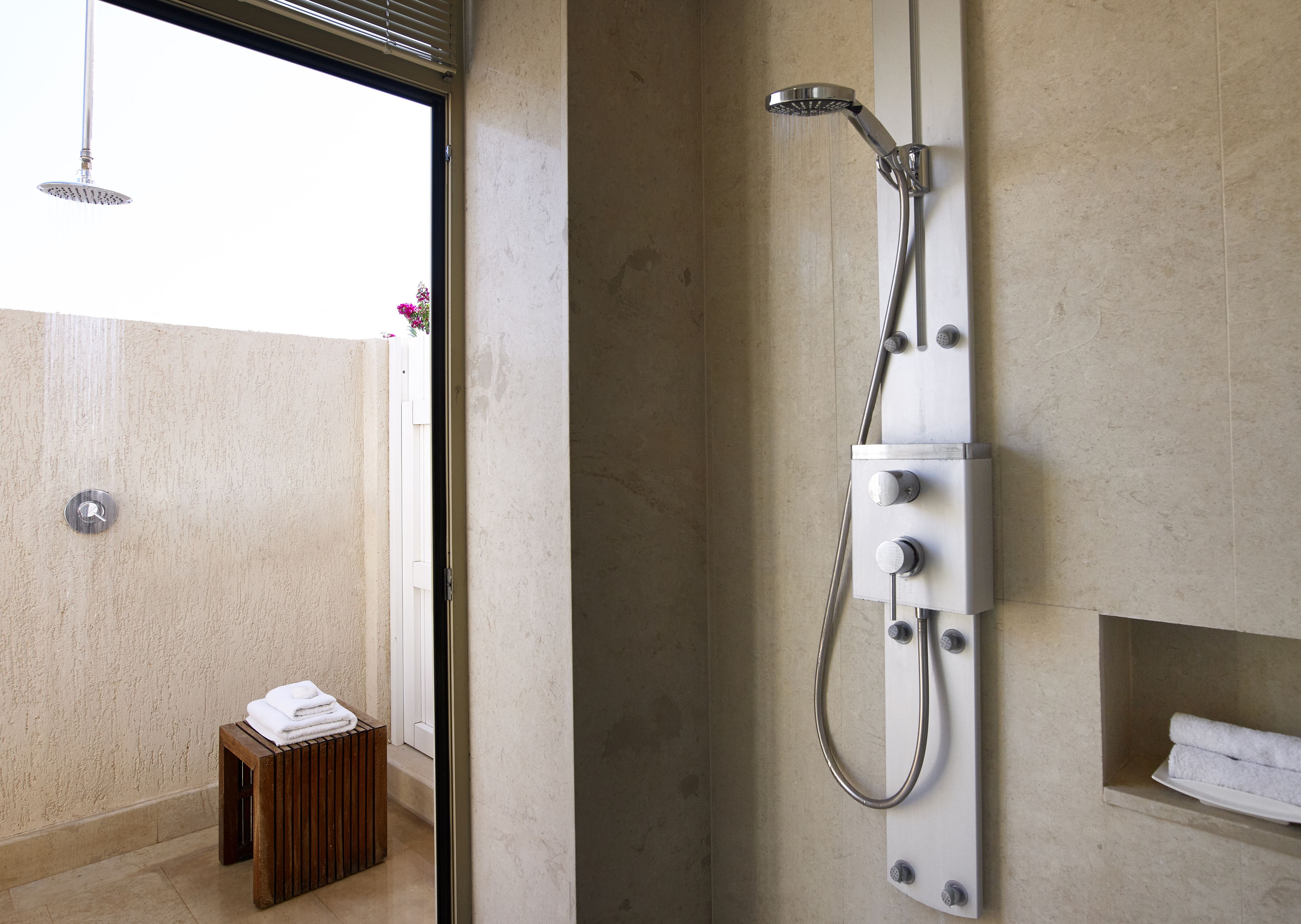 Un baño moderno con ducha, un taburete de madera pequeño y vistas al exterior.
