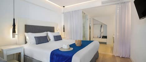 A modern hotel room with a large bed, bedside tables, a flat-screen TV, and a bathroom visible through a glass door.
