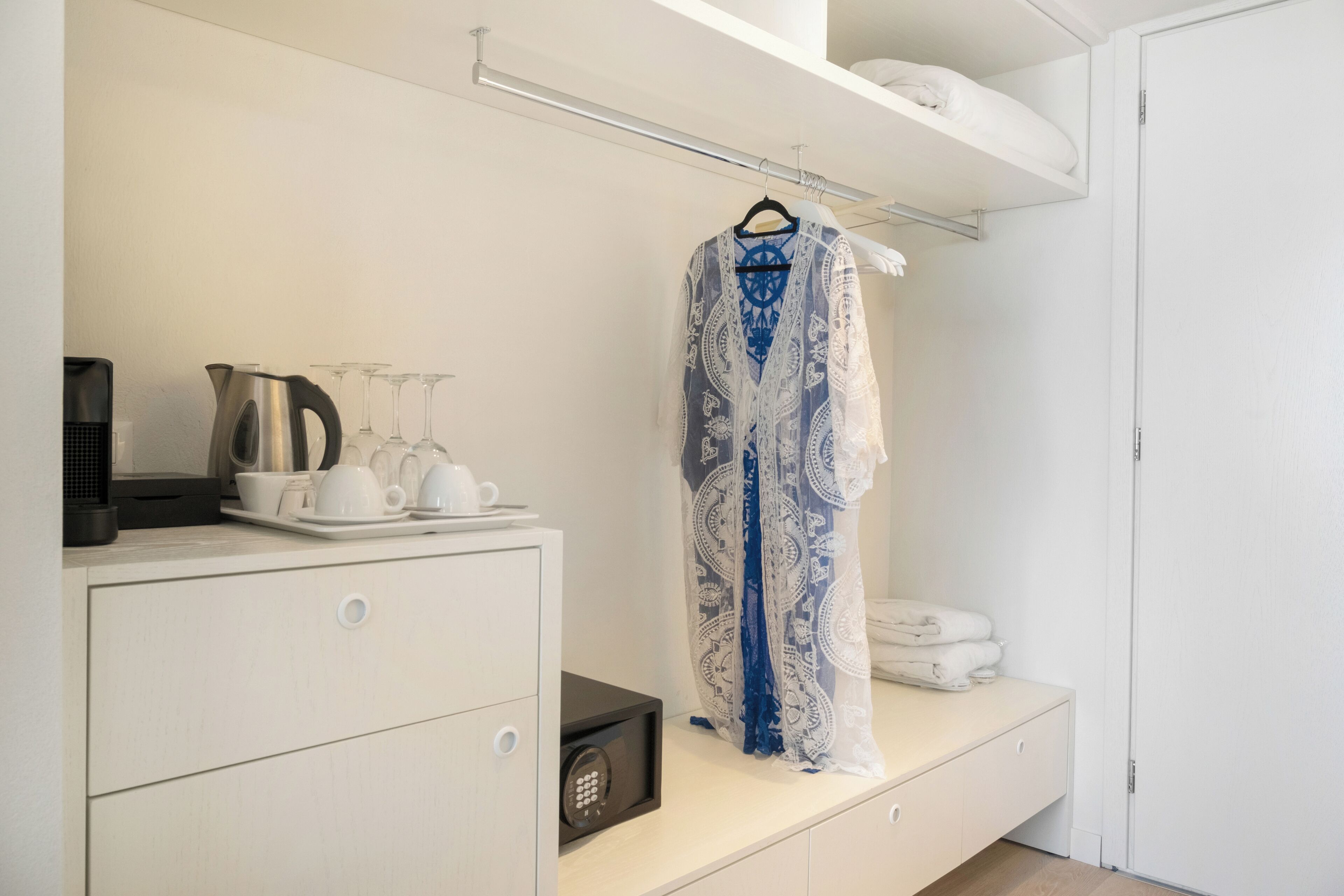 Une chambre d’hôtel équipée d’un minibar, d’un peignoir et d’un lit avec du linge de maison blanc.