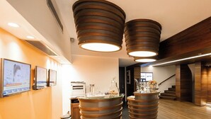A modern hotel lobby with a central reception desk, two large cylindrical light fixtures, and a staircase leading to upper floors. - Beyond Hotel - Boutique Class - Special Class (Izmir)
