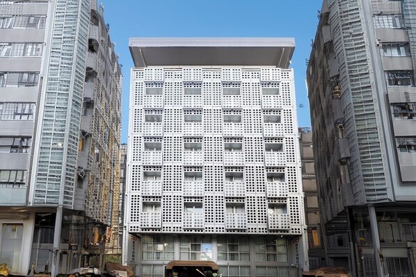 Ein mehrstöckiges Gebäude mit einer rasterförmigen Fassade, zahlreichen Fenstern und einem flachen Dach.