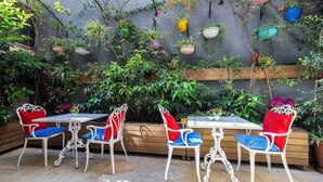 An outdoor patio with white metal chairs and tables, surrounded by lush greenery and hanging planters. - Beyond Hotel - Boutique Class - Special Class (Izmir)