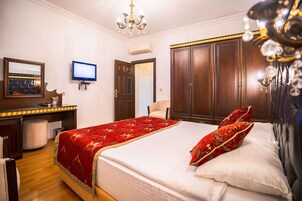 A hotel room with a bed, a desk with a computer, a TV, and a wardrobe.
