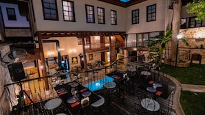 Un restaurante con terraza, piscina y un muro de piedra.
