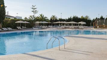 Una piscina al aire libre de temporada, sombrillas