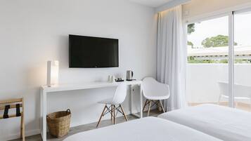 Habitación de hotel con cama, escritorio con televisor, silla y vista al exterior.