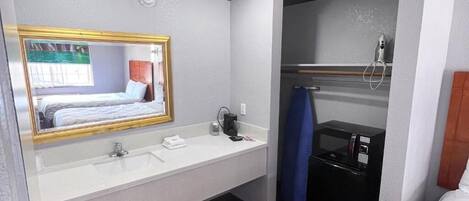 Un baño de hotel con un espejo grande, un lavabo, una ducha y una cama.