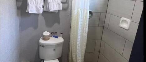 A small bathroom with a toilet, a shower curtain, and a towel rack.