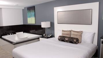 Una habitación de hotel moderna con una cama grande, un baño separado con bañera y una obra de arte colgada en la pared.