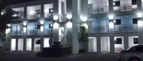 Un hotel de varios pisos con balcones, un estacionamiento y un patio central.