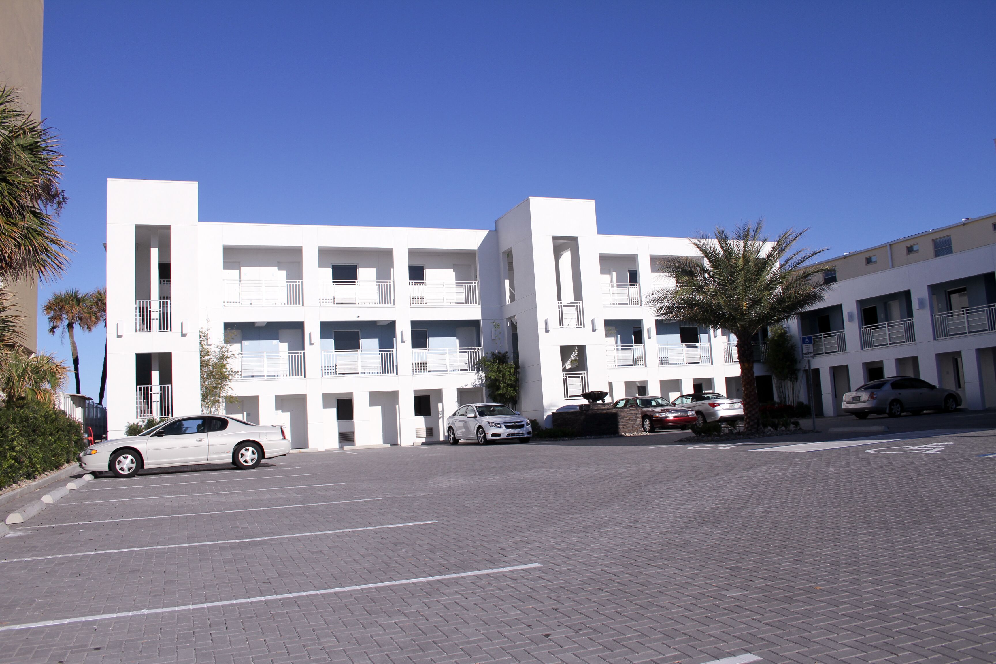 A modern building with multiple balconies and a parking area.