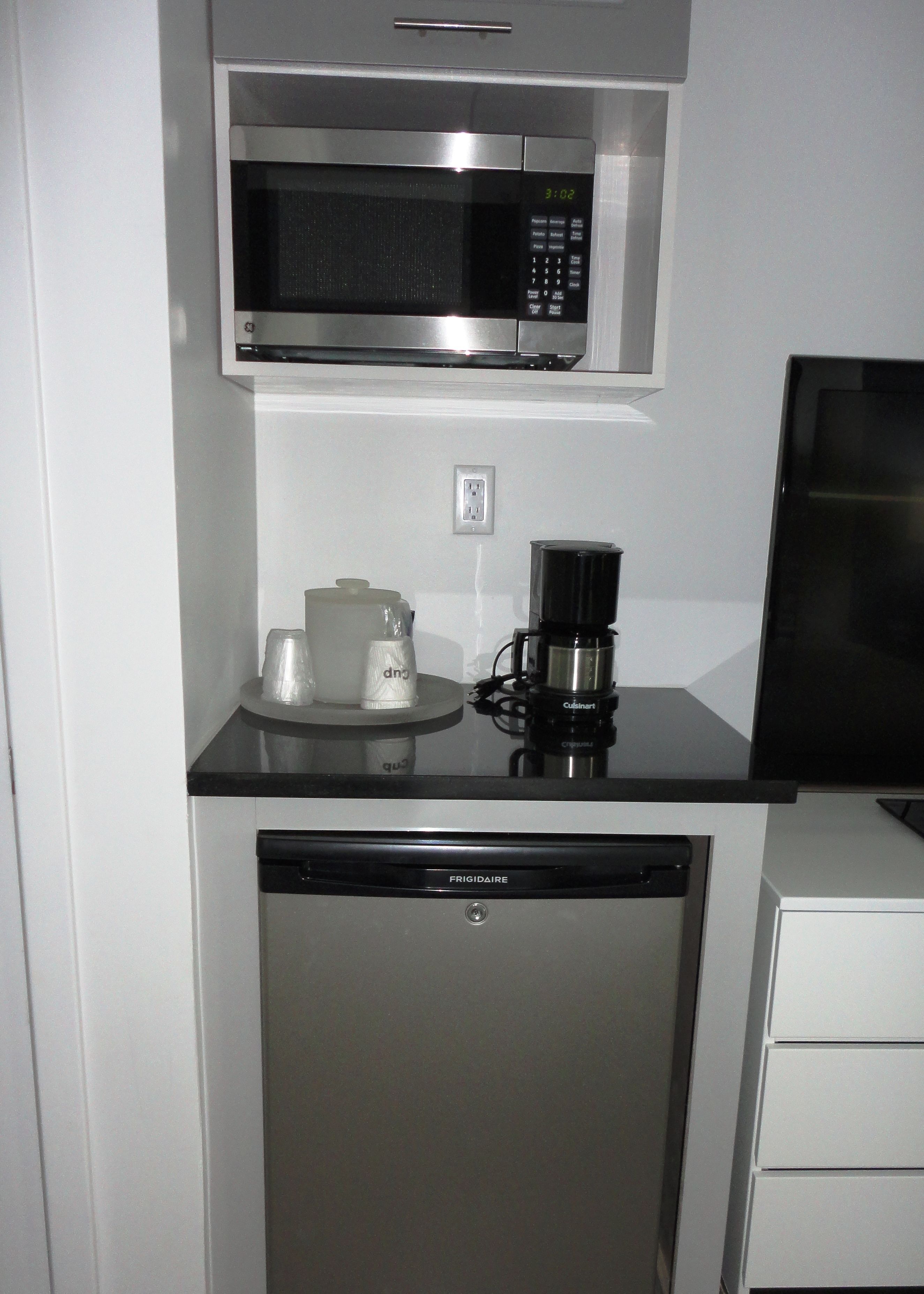 A compact kitchen with a built-in microwave, a coffee maker, and a dishwasher.