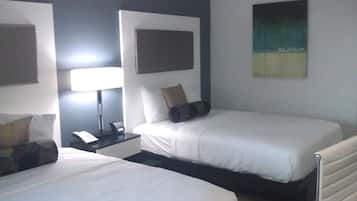A hotel room with two single beds, a bedside table with a lamp, a phone, and a wall-mounted artwork.