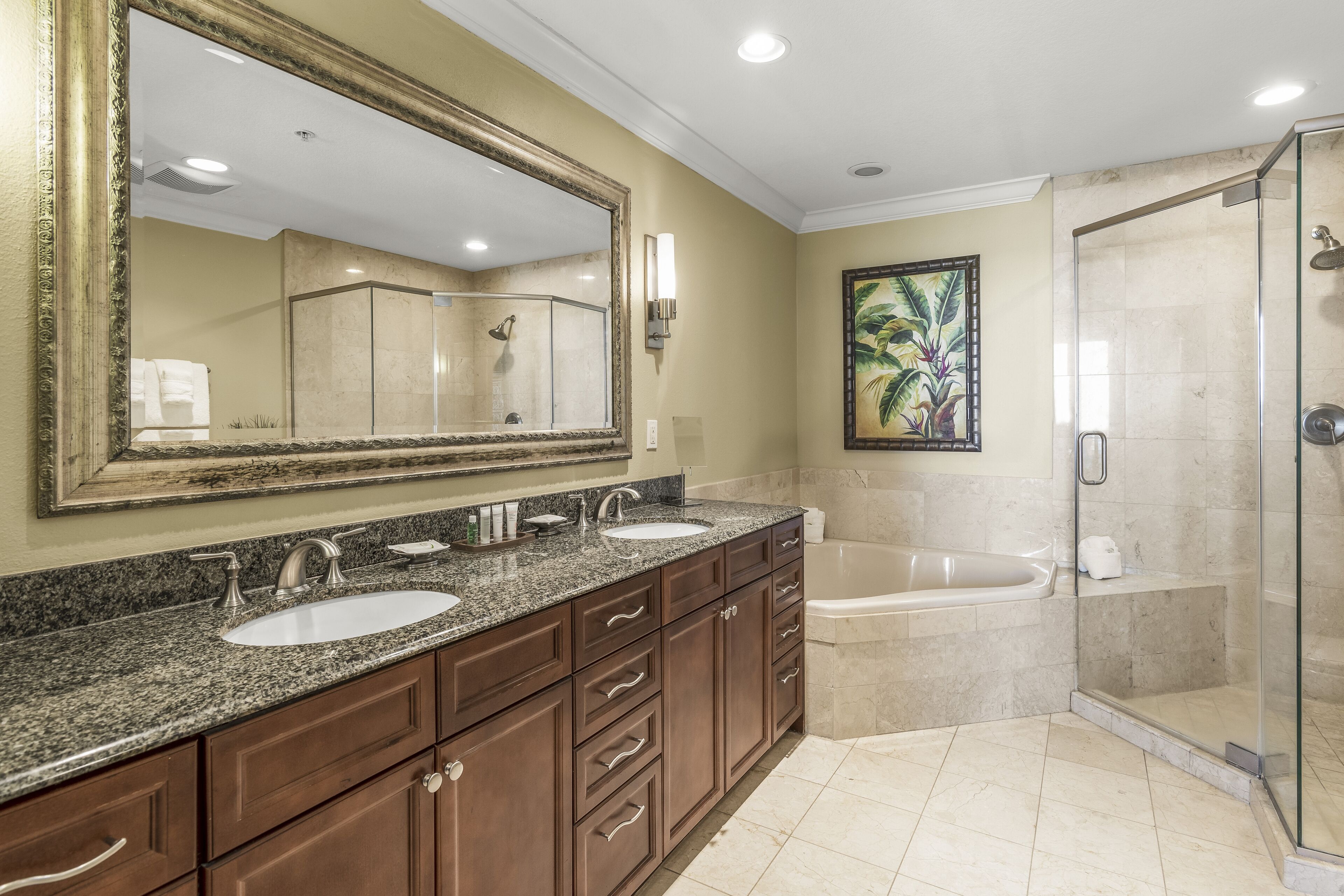 A modern bathroom with a large mirror, dual sinks, a bathtub, and a glass-enclosed shower.