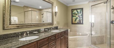 A modern bathroom with a large mirror, dual sinks, a bathtub, and a glass-enclosed shower.