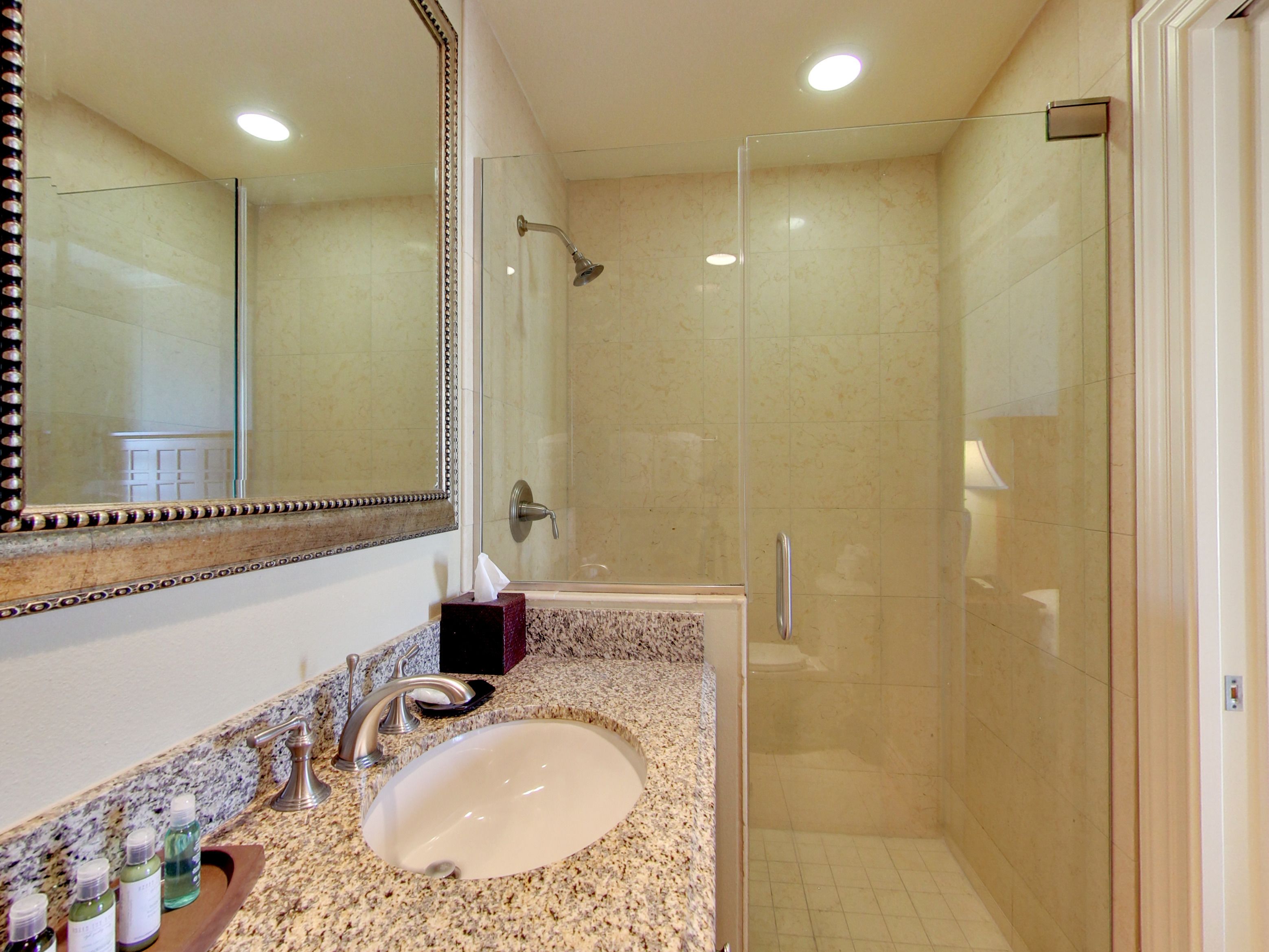 A bathroom with a sink, mirror, and shower.
