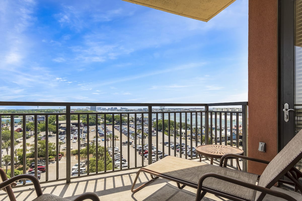 A balcony with a view of a parking lot and a body of water.