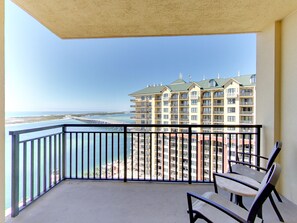 A balcony with a view of a beach and a hotel in the background. - Emerald Grande Condominiums at HarborWalk Village (Destin)