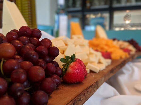 Una tabla de madera con uvas, fresas y queso.