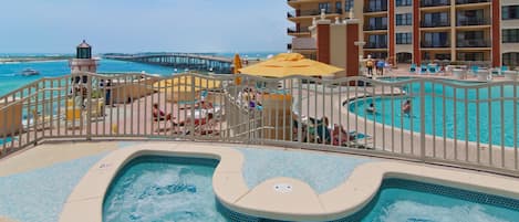 A hotel pool area with a hot tub, lounge chairs, and a view of the ocean.