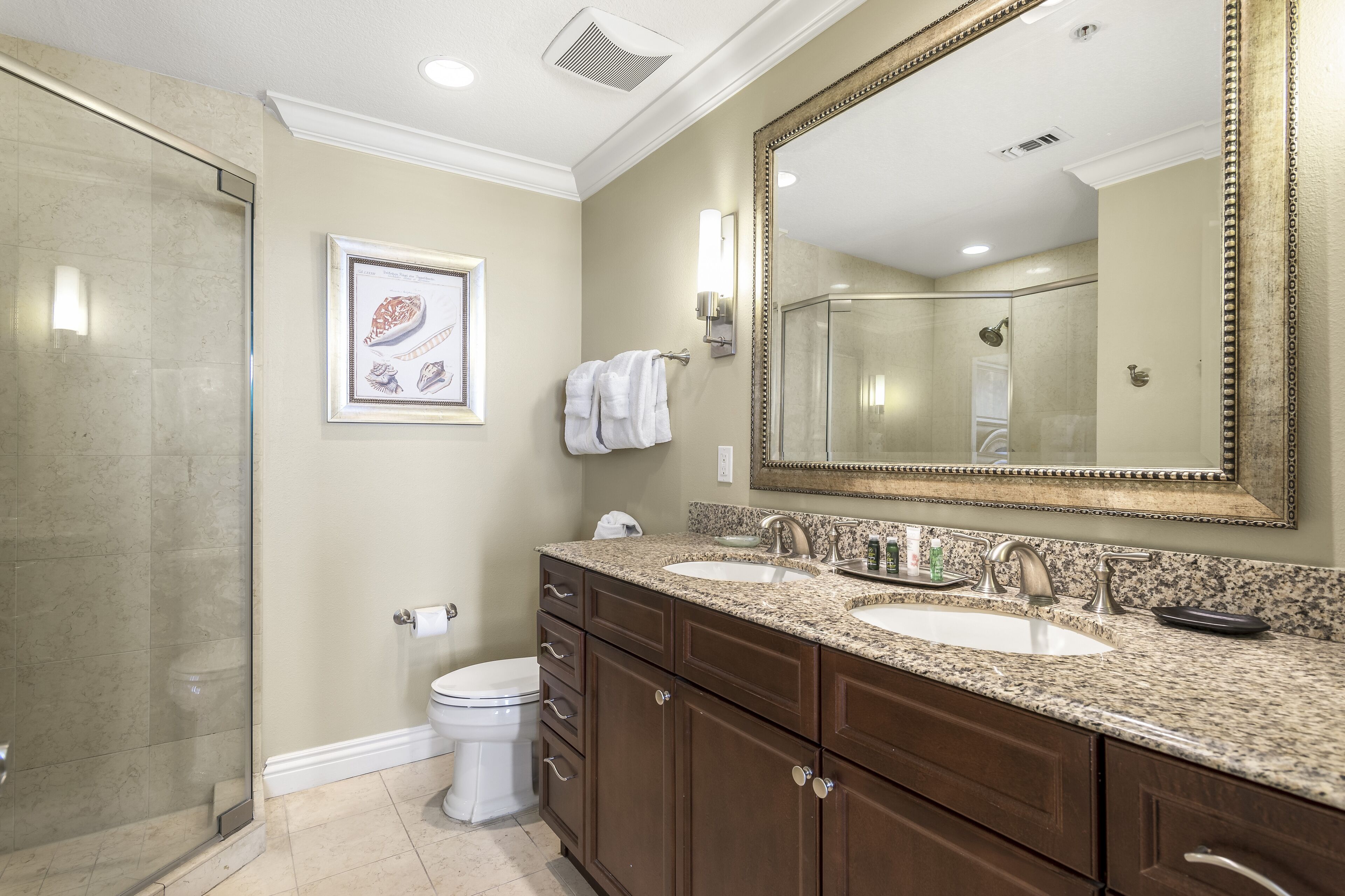 A bathroom with two sinks, a large mirror, and a shower.