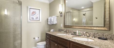 A bathroom with two sinks, a large mirror, and a shower.