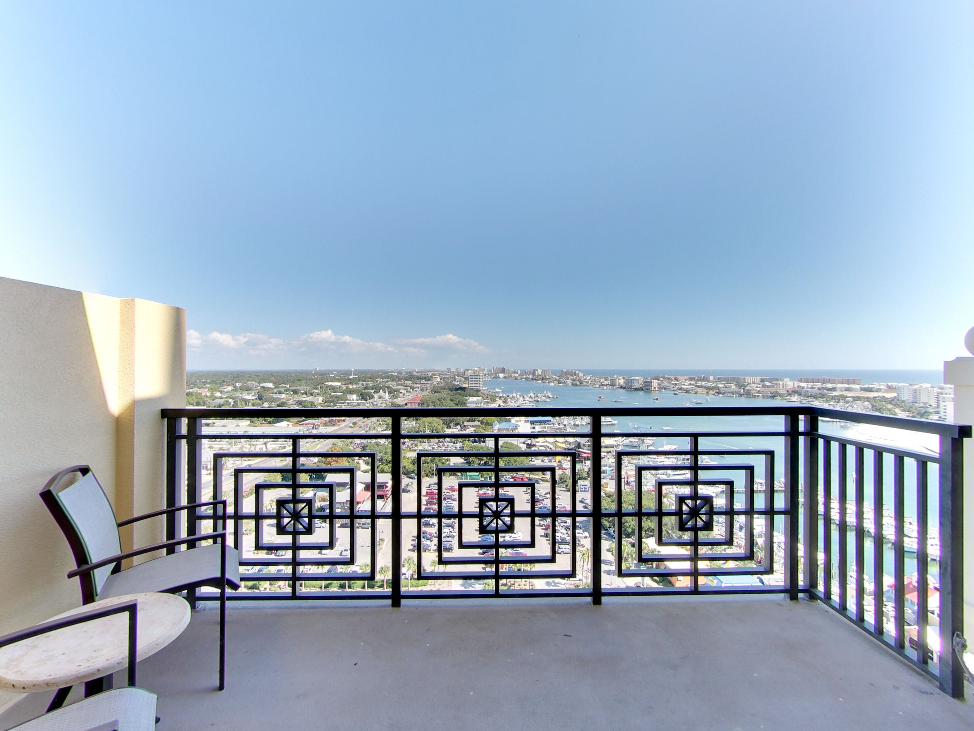 A balcony with a metal railing and a chair, overlooking a marina and cityscape.