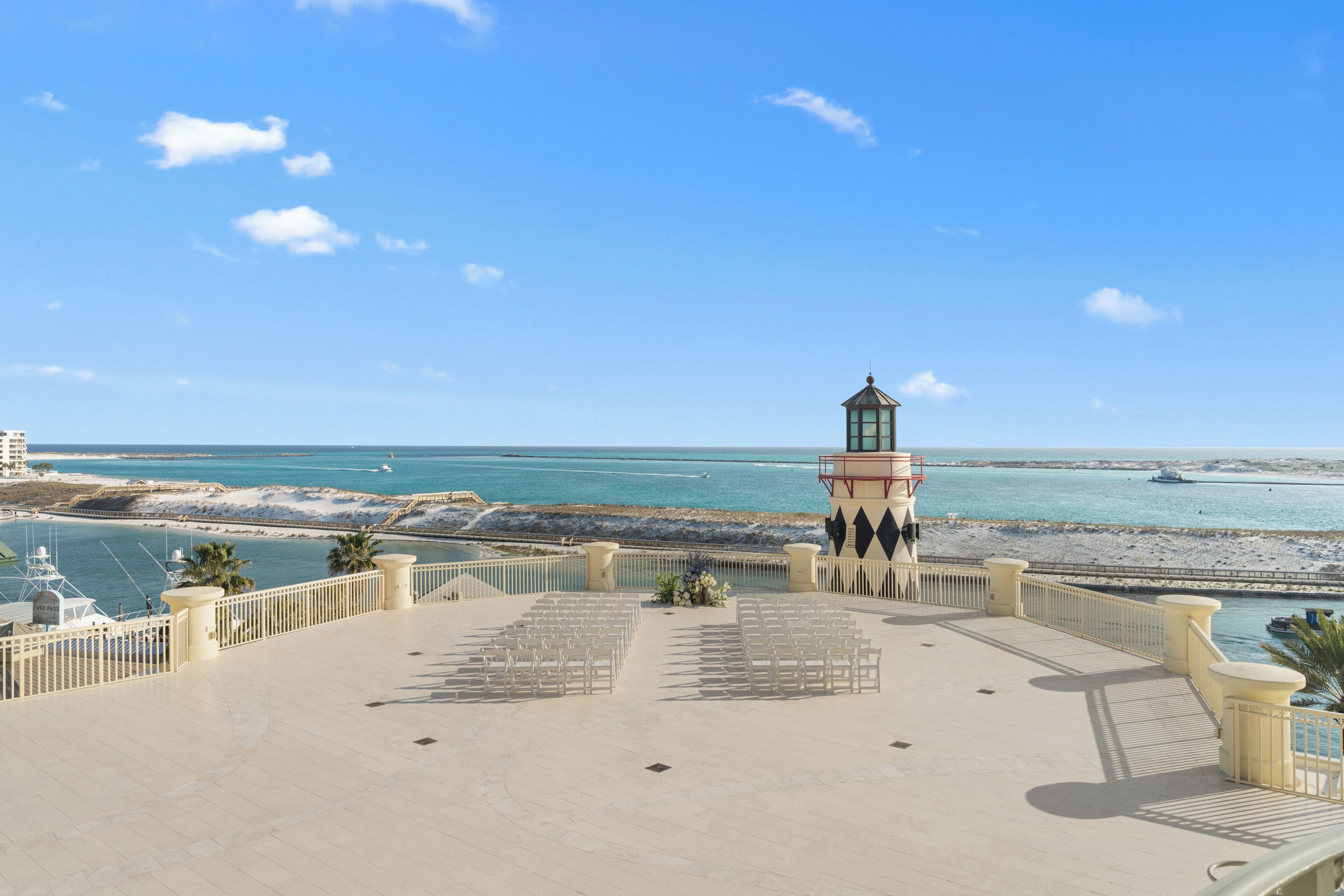 A seaside promenade with a lighthouse, a beach, and a clear sky.