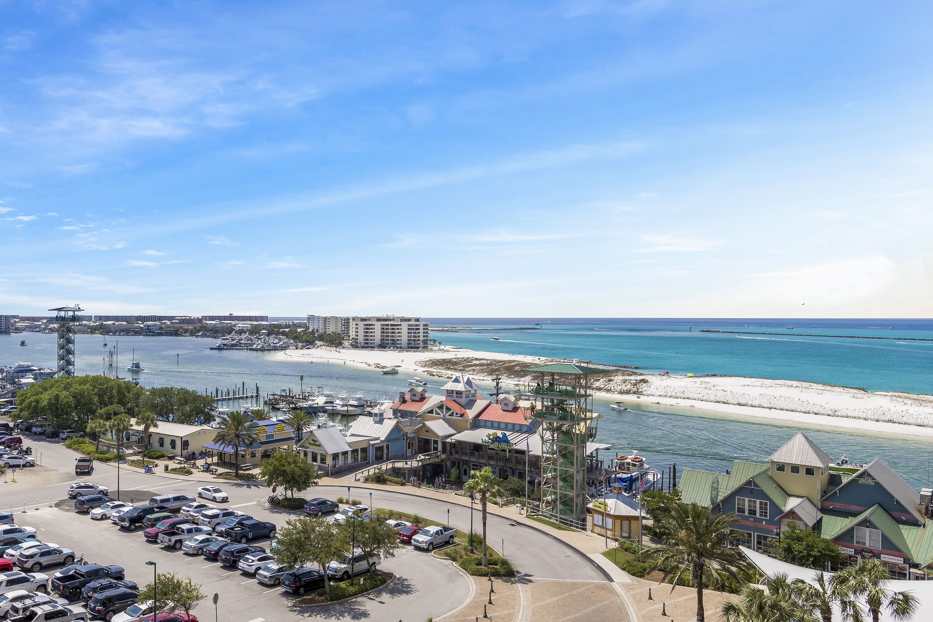 A coastal town with a marina, beach, and various buildings including a hotel with a distinctive tower and multiple stories.