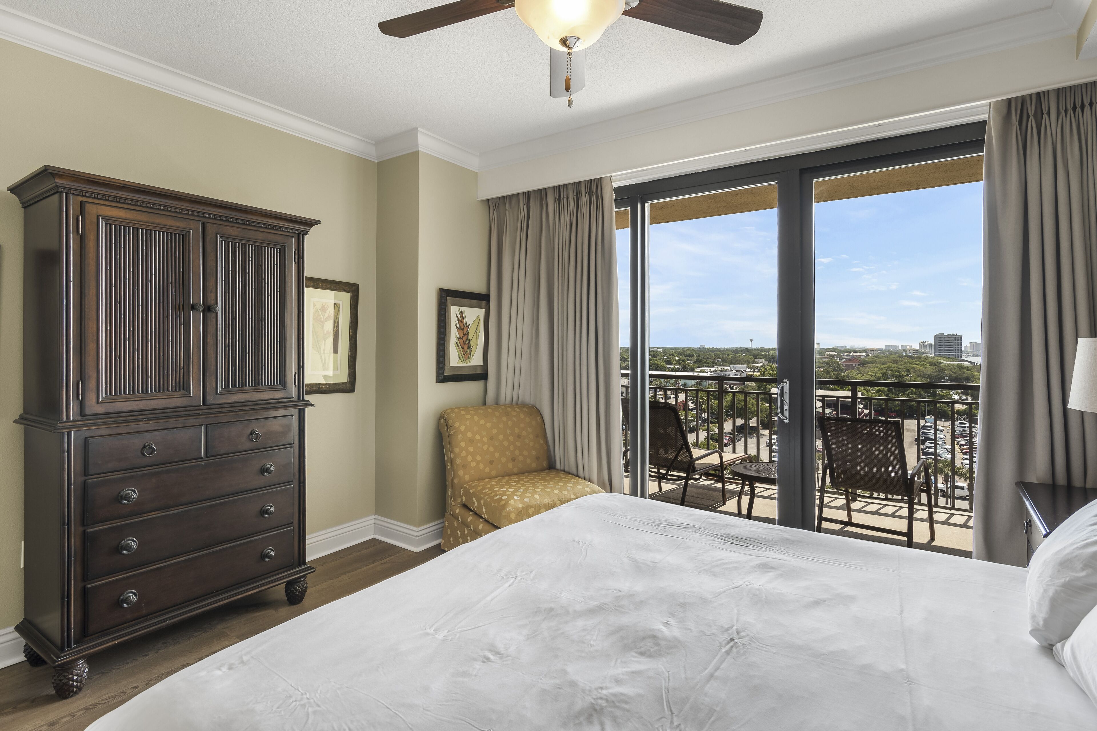 Una habitación de hotel con una cama grande, un aparador, una silla y un balcón con vista a la ciudad.