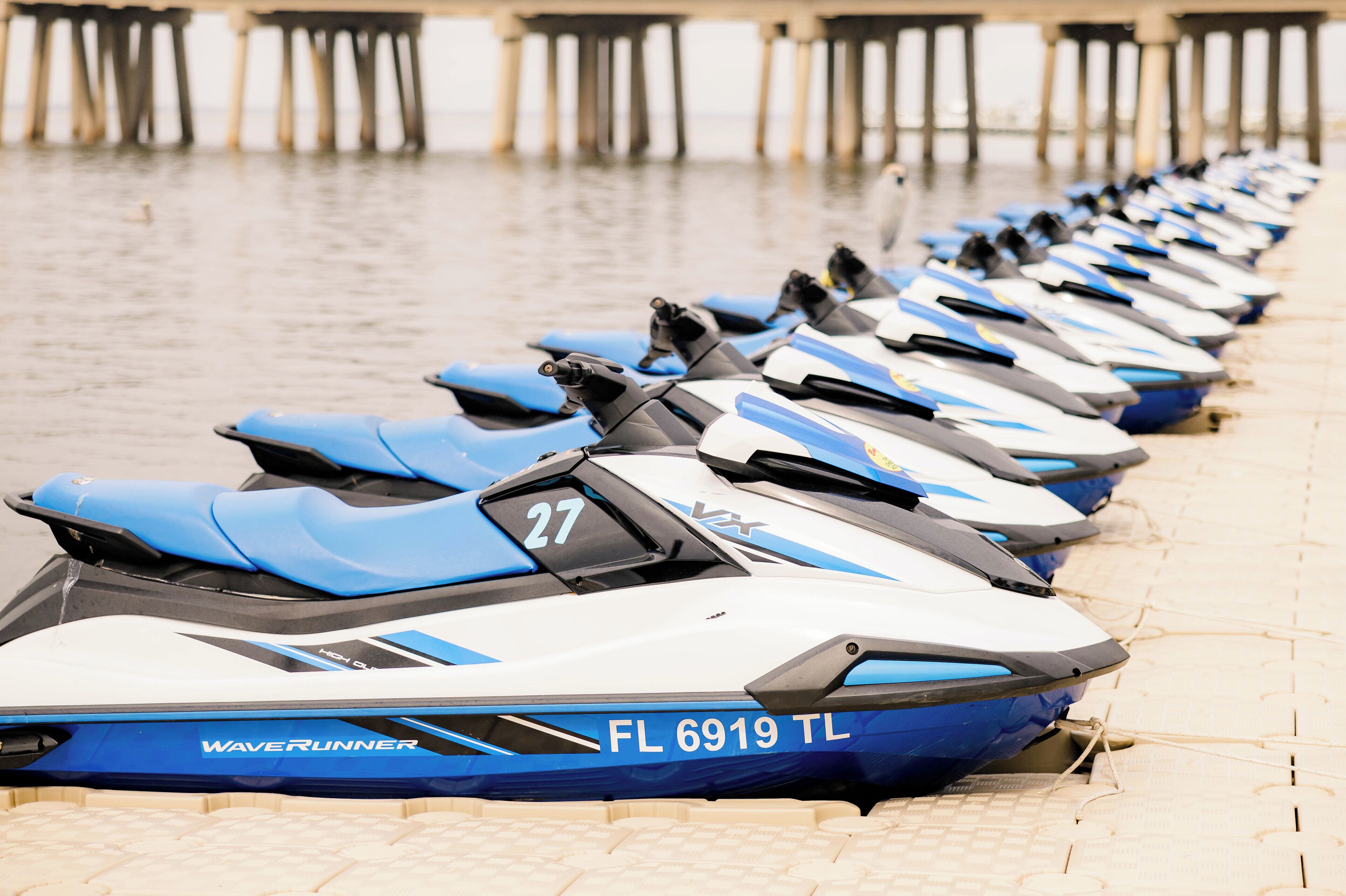 Eine Reihe von Jetskis mit den Nummern 27, 28 und 29 liegen an einem Steg festgemacht.