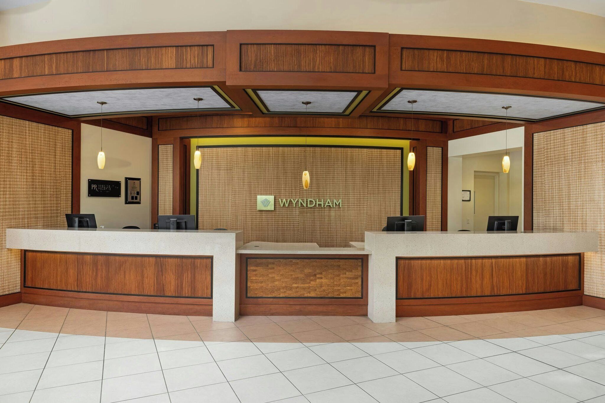 A reception area with a wooden reception desk, a sign reading 'WYNDHAM,' and a tiled floor.