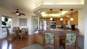 A modern kitchen with a central island, wooden chairs, and pendant lighting. - Club Wyndham Bali Hai Villas (Princeville)