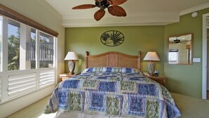 A bedroom with a large bed, two bedside lamps, a ceiling fan, a wall clock, and a window with blinds. - Club Wyndham Bali Hai Villas (Princeville)