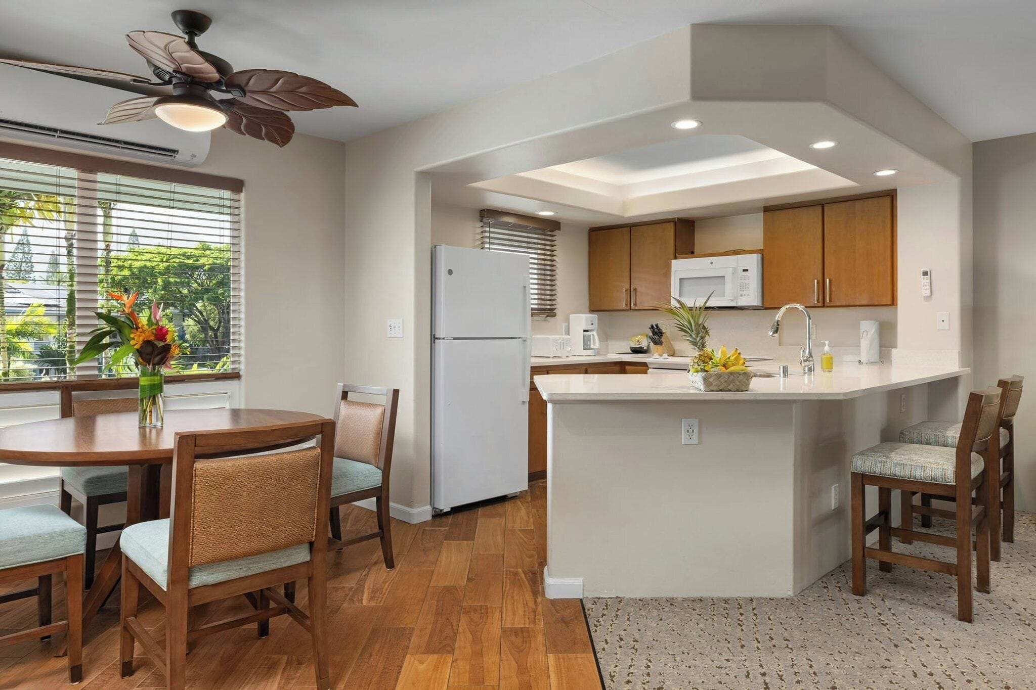 A modern kitchen with wooden cabinets, a built-in island, and a dining area with a table and chairs.