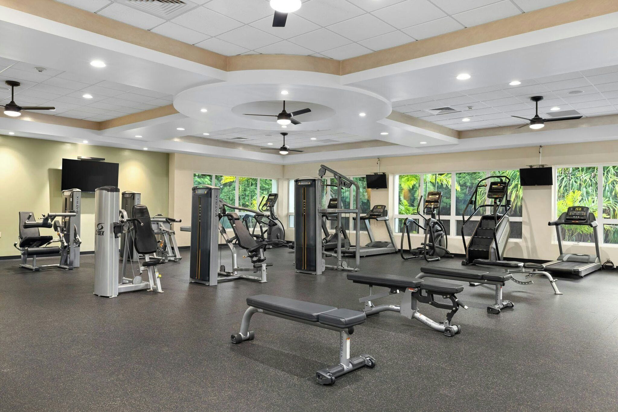 A gym with various exercise equipment, including treadmills, weight machines, and benches.