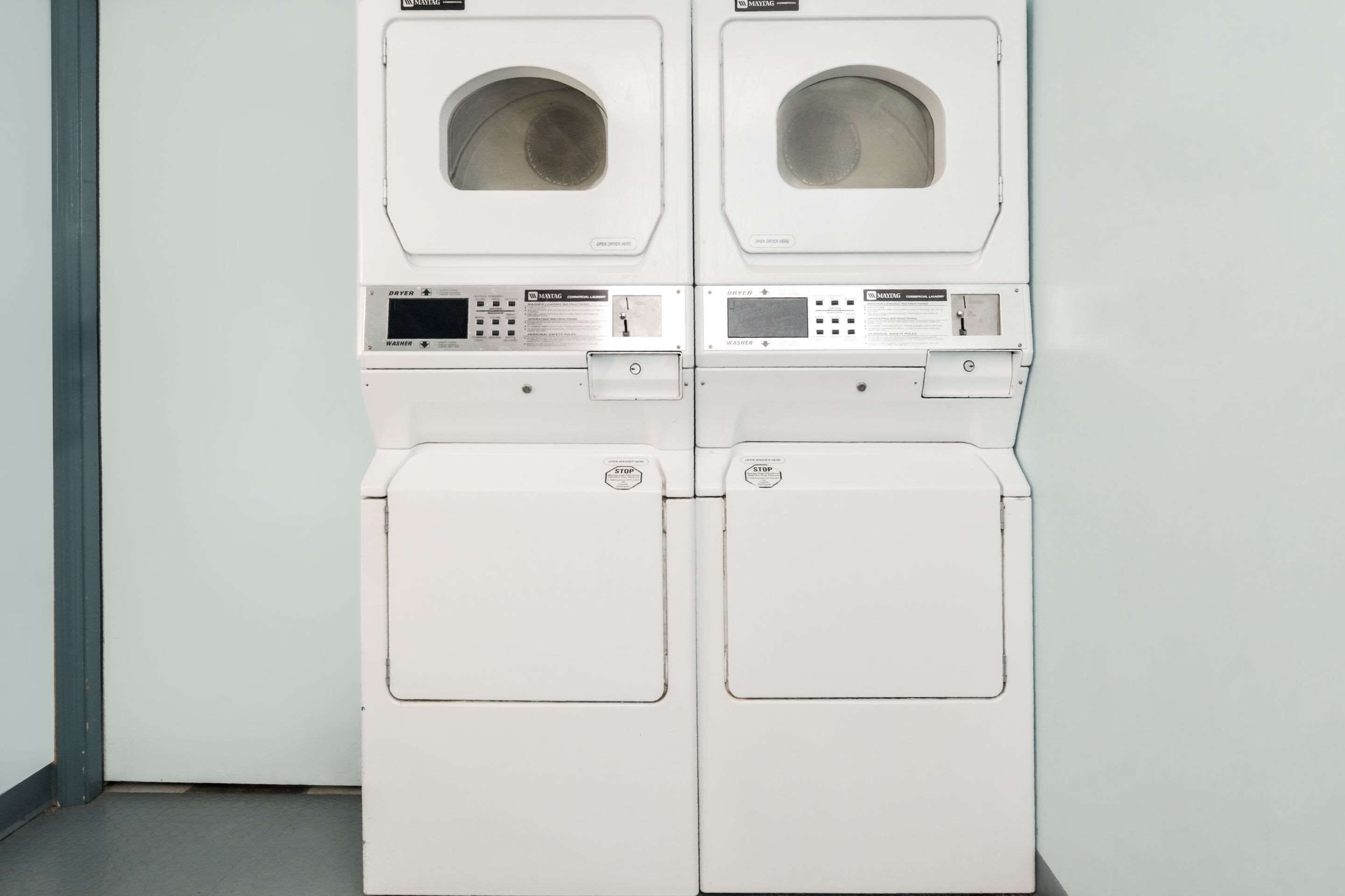 A pair of white front-loading washing machines with control panels and a door.