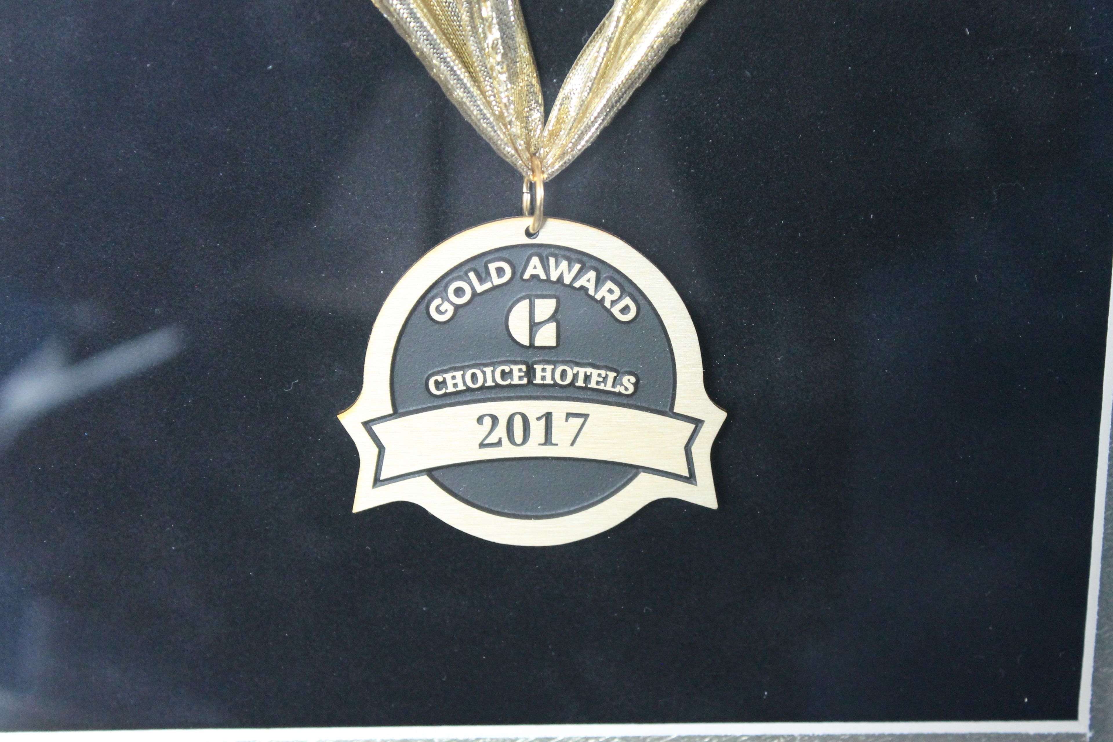 A gold award medal with the text "Gold Award Choice Hotels 2017" on a black background.