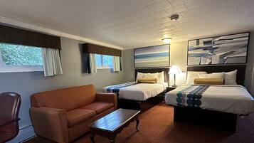 A hotel room with two beds, a sofa, a chair, and a small table.