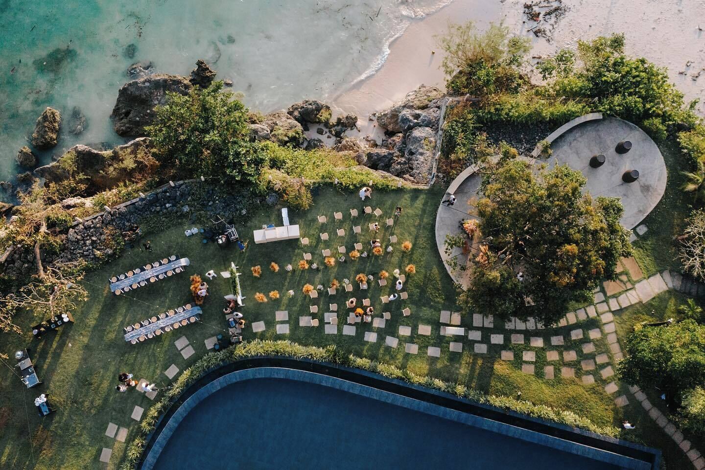 Vista aérea de un complejo turístico con piscina, zonas de estar al aire libre y una playa.