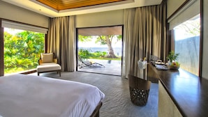 Habitación de hotel con cama, una silla, mesa de comedor y vista panorámica, además de un gran ventanal con cortinas.