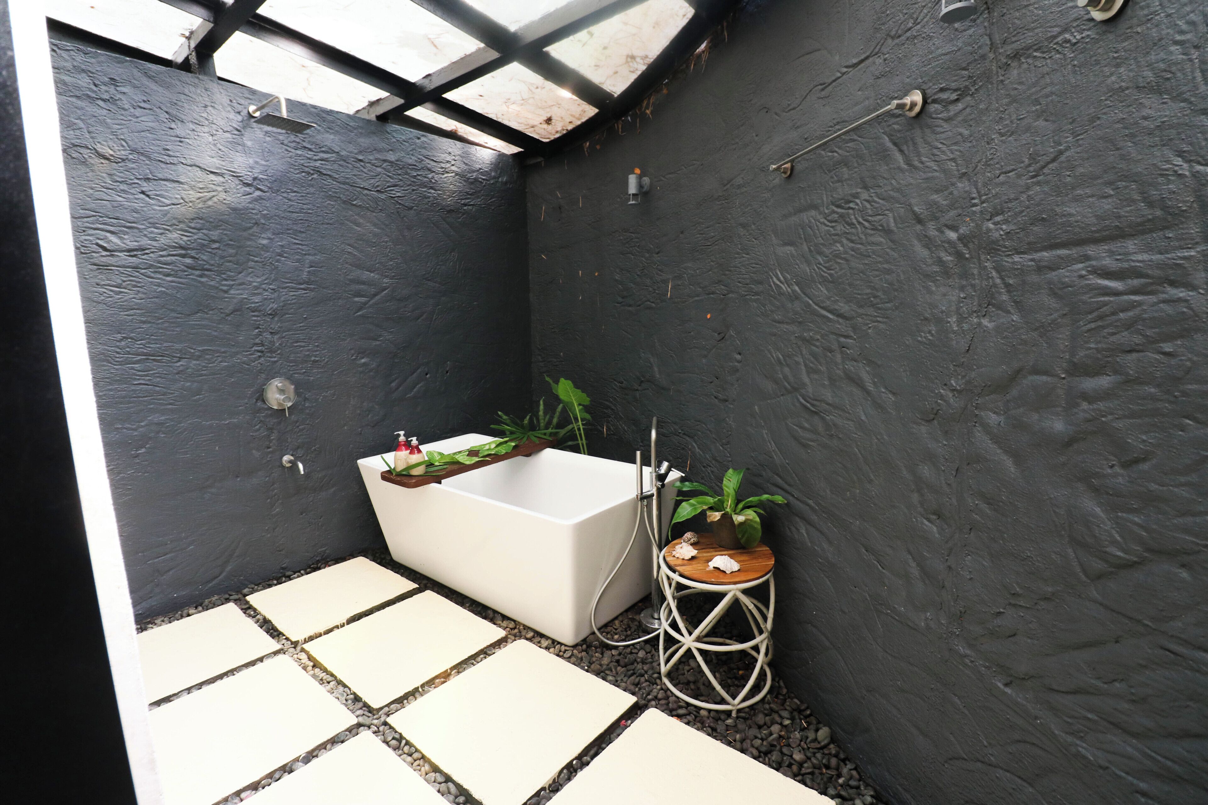 Uma casa de banho moderna com uma banheira branca, um banquinho de madeira e uma planta em vaso.