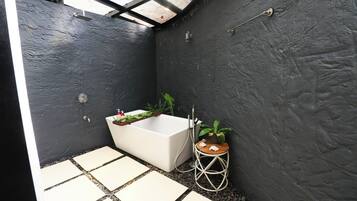 Uma casa de banho moderna com uma banheira branca, um banquinho de madeira e uma planta em vaso.