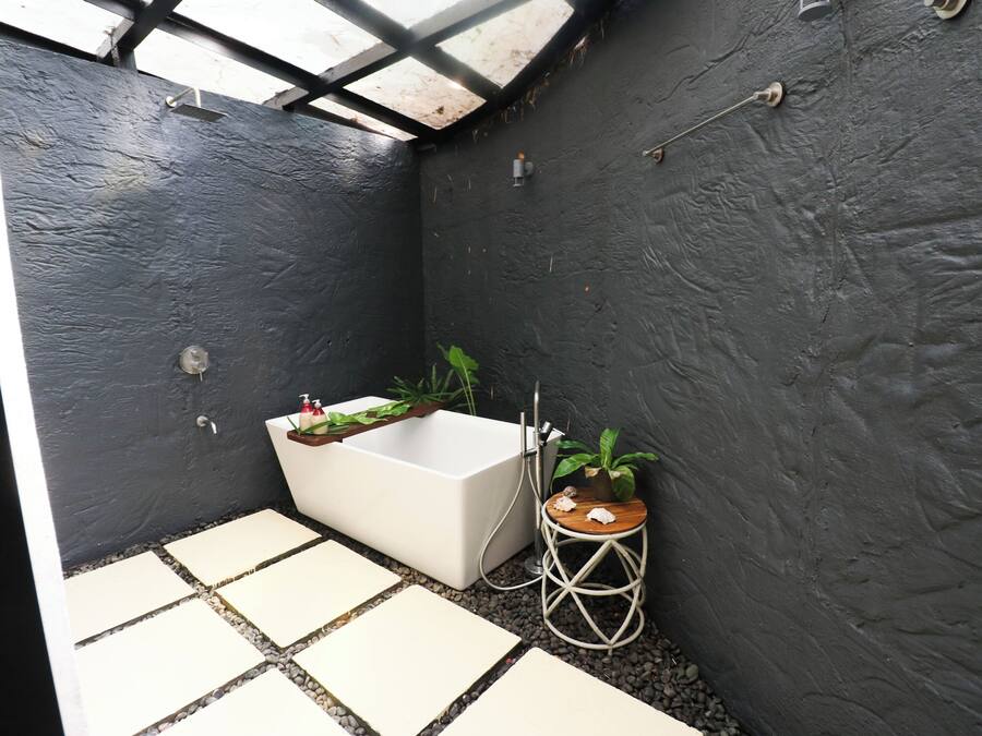 Uma casa de banho moderna com uma banheira branca, um banquinho de madeira e uma planta em vaso.